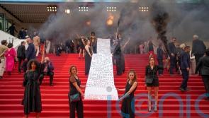 Female activists unfurl banner during Cannes red carpet protest