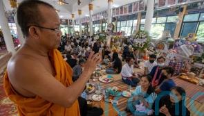 Mourners pray at Thai temple filled with keepsakes from nursery shooting victims