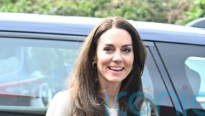 Kate helps fold baby clothes on visit to Baby Bank donation centre