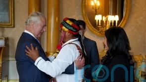 King gets feathered crown and hug ahead of coronation