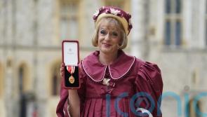 Grayson Perry accepts knighthood in burgundy taffeta dress in honour of the King