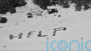 Three men rescued from Pacific island after creating ‘help’ sign on beach