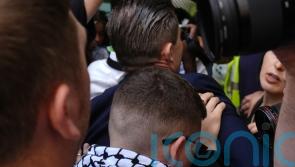 Kneecap greeted by hundreds at court as rap group member faces terrorism charge