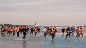 Migrants run across beach to board dinghy in the Channel