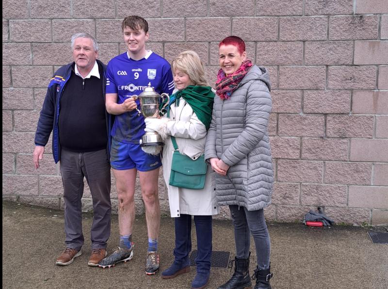 Thurles Sarsfields captain Cian Stakelum accepts the cup from Rose Young, with Joe O'Sullivan and Catherine Dunne in attendance 