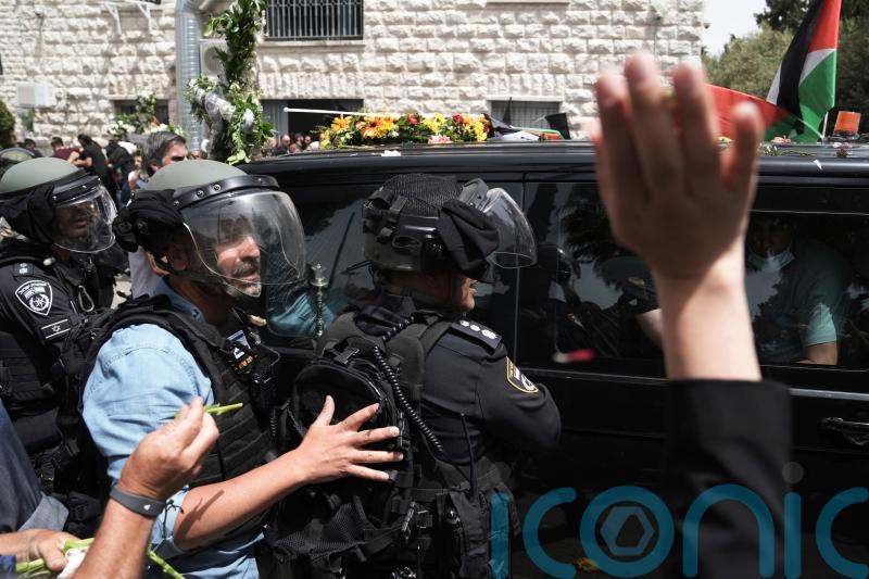 Coffin is dropped amid scuffles before Al Jazeera journalist is laid to rest