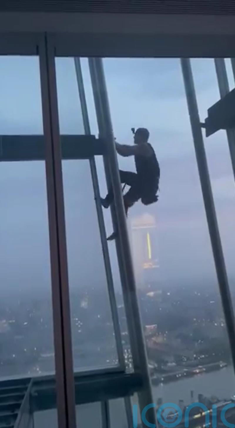 Couple wave at barefoot man climbing past their window at the Shard 40 floors up