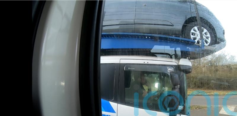 Driver caught using elbow to steer car transporter on motorway