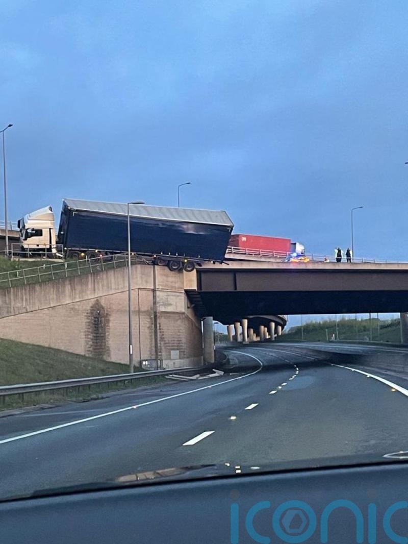 Lorry left hanging above A road after crashing into bridge barrier