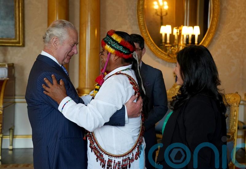 King gets feathered crown and hug ahead of coronation