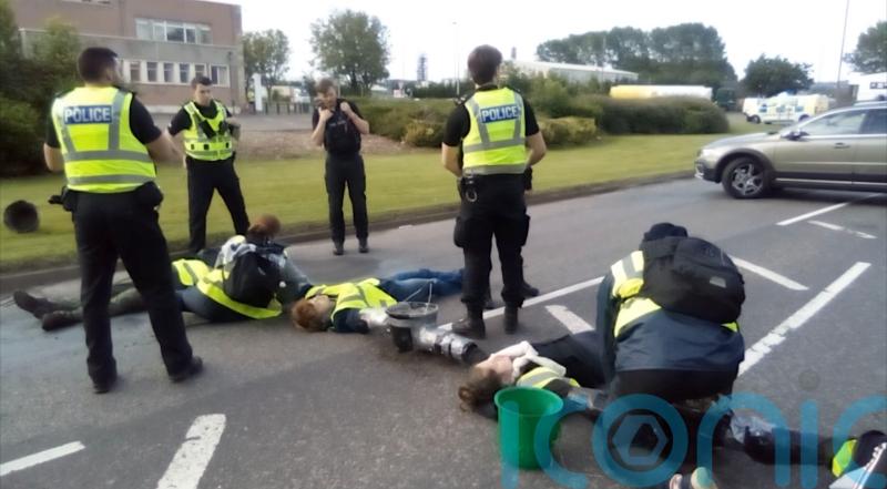 Climate protesters ‘concrete’ themselves to road to block refinery