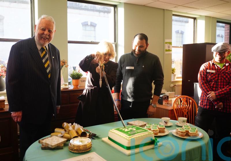 Queen cuts cake with sword as she celebrates charity’s 25th birthday