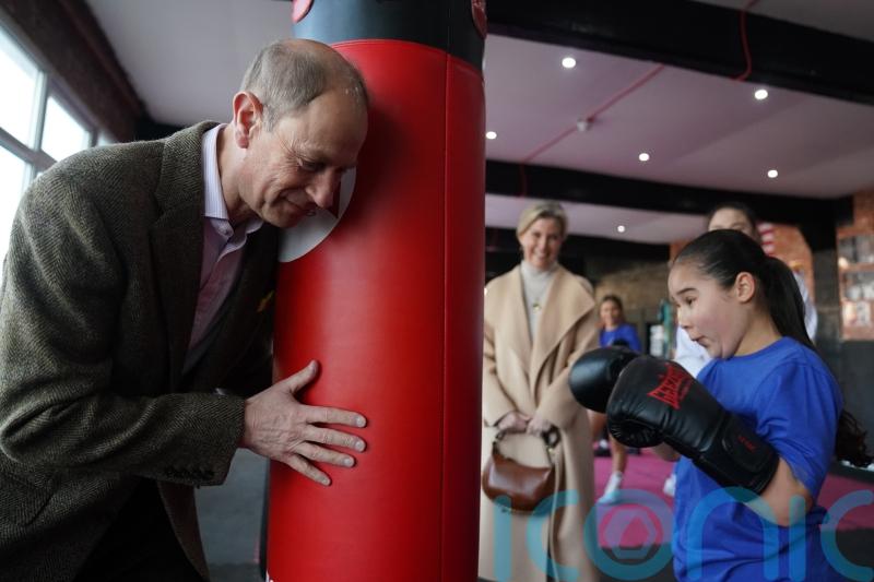 Edward holds the punchbag in sparring session with young boxer