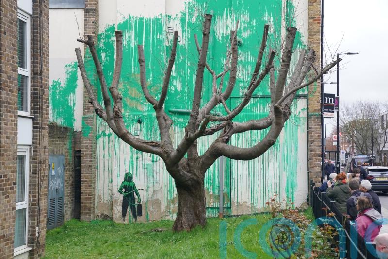 Banksy mural covered with plastic sheeting and wooden boards