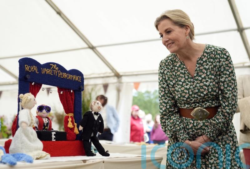 Sophie examines knitted versions of herself and husband at flower show