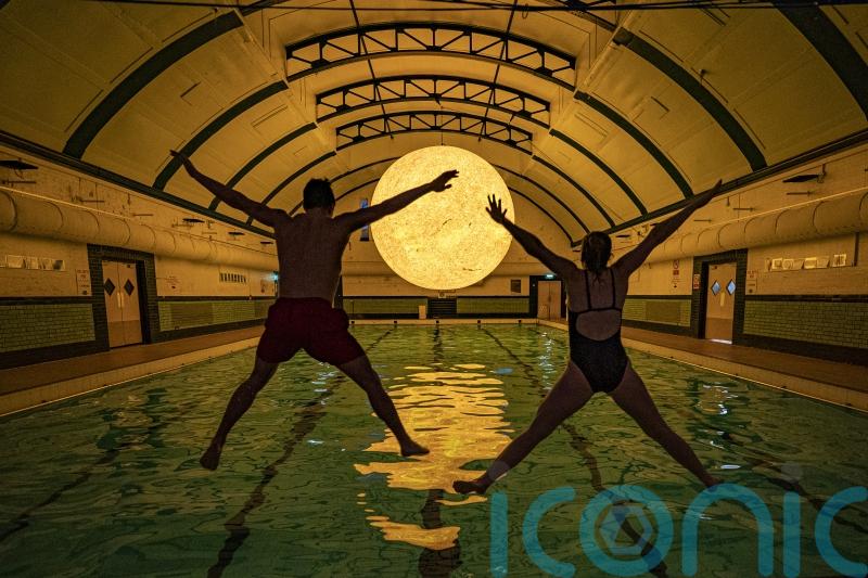 Sun artwork suspended above water at community swimming pool